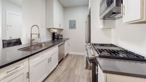 a kitchen with white cabinets and stainless steel appliances and a sink at Charter Oaks Apartments, California