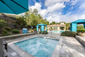 a swimming pool with two blue umbrellas and a house in the background at Alta Vista, Escondido