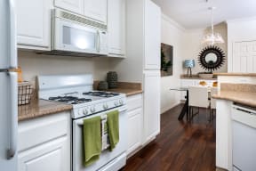 Kitchen with Wood-Style Flooring, Granite Countertops, White Appliances and Cabinets, and Access to Dining Area at Barrington Place, Rancho Cucamonga, 91739