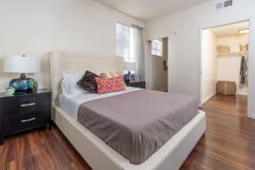 Bedroom With Hardwood-Style Flooring, Bed, Nightstands with Lamps, Spacious Closet, Window, And Attached Bathroom. at Barrington Place, Rancho Cucamonga, CA, 91739