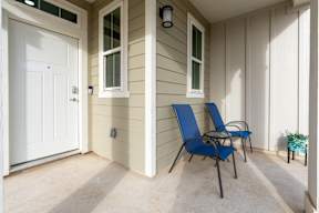 a porch with two blue chairs and a white door at Mihir Taylor, Texas 76574