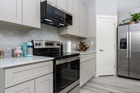 model kitchen with stainless steel appliances and white cabinets at Mihir Taylor, Taylor, TX