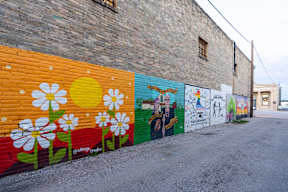 a mural on the side of a brick wall with flowers at Mihir Taylor, Taylor, TX
