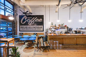 a coffee shop with blue tables and a sign that reads coffee reduces fatigue at Mihir Taylor, Texas 76574