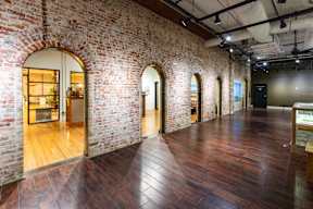 a large room with wood floors and brick walls and arched doorways at Mihir Taylor, Texas