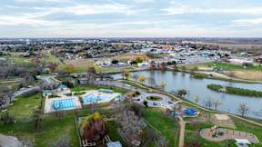 an aerial view of a park with a lake and a city in the background at Mihir Taylor, Taylor, 76574