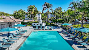 A large swimming pool surrounded by lounge chairs and umbrellas at Missions at Chino Hills Apartments, California