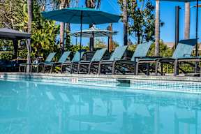 A pool with blue umbrellas and chairs. at Missions at Chino Hills Apartments, California, 91709