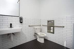 A white toilet in a bathroom with a white sink and a mirror at Missions at Chino Hills Apartments, Chino Hills, 91709