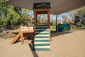 A playground with a wooden structure and a green slide at Missions at Chino Hills Apartments, Chino Hills, CA, 91709