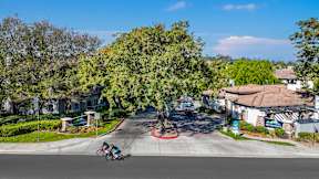 A street view of a residential area with a person riding a bicycle at Missions at Chino Hills Apartments, Chino Hills, California