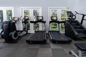 A gym with treadmills, elliptical machines, and a stationary bike at Missions at Chino Hills Apartments, Chino Hills, California