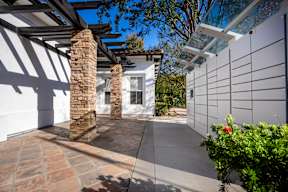 A patio with a white wall, a stone pillar, and a glass roof at Missions at Chino Hills Apartments, Chino Hills, CA, 91709