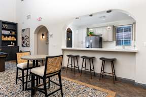 A kitchen with a bar area featuring a black fridge and bar stools. at Sonoma at Mapleton Apartments, West Murrieta California