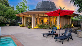 A house with a pool and a red umbrella.