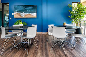 A dining room with a large painting of a beach scene on the wall.