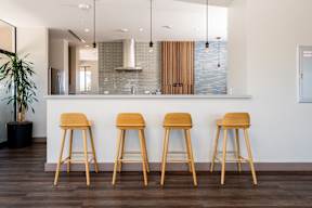 Three wooden bar stools are placed in front of a bar.