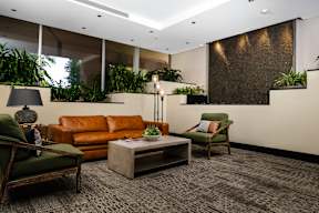 A living room with a brown couch, a green chair, and a grey coffee table.