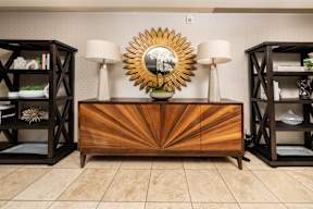 A wooden dresser with a sunburst mirror on top is flanked by two bookcases.