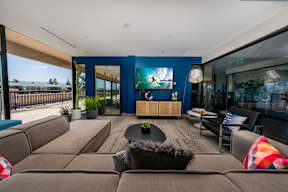 A modern living room with a brown sofa set and a flat screen TV mounted on the wall.