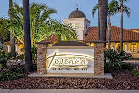 A sign that says "Toséana at Rancho Del Rey" is in front of a building with palm trees.
