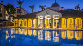 A house with a pool in front of it is lit up at night.