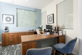 A room with a desk, chairs and a phone.