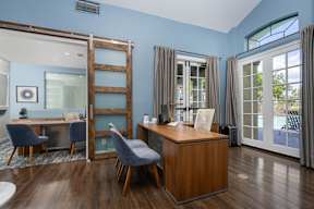 A room with a desk and chairs with a blue wall.