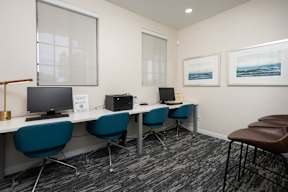 A room with a desk, chairs, and computers.