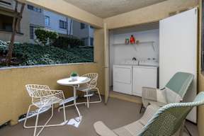 A small balcony with a table and chairs.