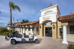 A white golf cart is parked in front of a building with a sign that reads "Teresa.".