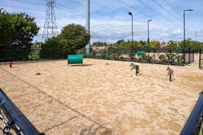 A tennis court with a green bench and a fence.
