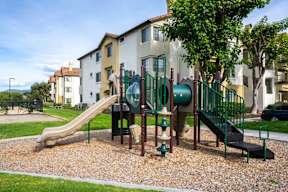 A playground with a green slide and a brown slide.