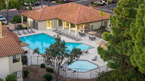 A large outdoor swimming pool surrounded by a fence and lounge chairs.