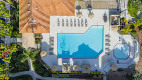 An aerial view of a swimming pool surrounded by lounge chairs and umbrellas.