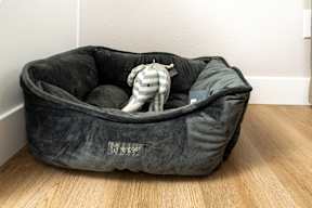 A grey dog bed with a white logo on it.