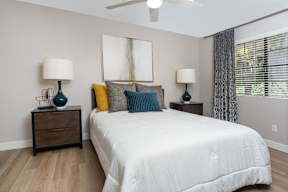 A bedroom with a bed, two nightstands, and a ceiling fan.