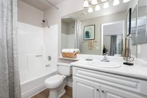 A white bathroom with a toilet, sink, and mirror.