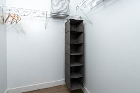 A white wall with a shelf and clothes hangers.