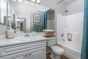 A white bathroom with a toilet, sink, and shower.