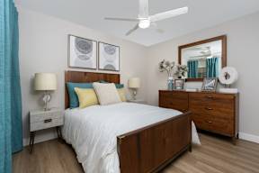 A bedroom with a bed, nightstands, and a ceiling fan.