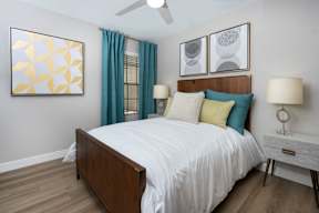 A bedroom with a bed, nightstand, and two framed pictures on the wall.