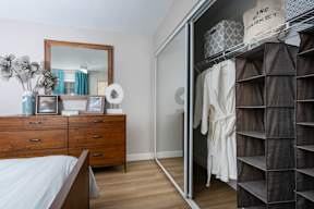 A bedroom with a bed, dresser, mirror, and closet.