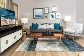 A living room with a grey couch, a wooden coffee table, and a painting on the wall.