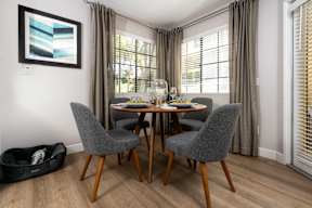 A dining room with a table set for two and a grey chair.