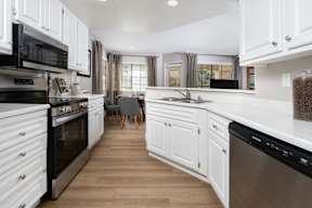 A modern kitchen with white cabinets and stainless steel appliances.
