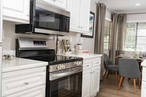 A modern kitchen with black and white appliances and a grey chair.