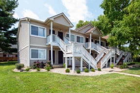 a house with stairs and a yard with grass and trees