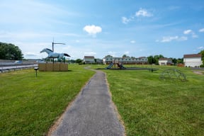 a path leading to a playground and a horse statue in a park