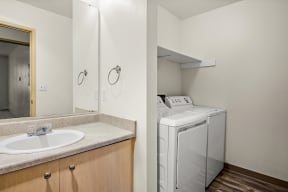 a bathroom with a sink and a washer and dryer at Mill Pond Apartments, Auburn, WA